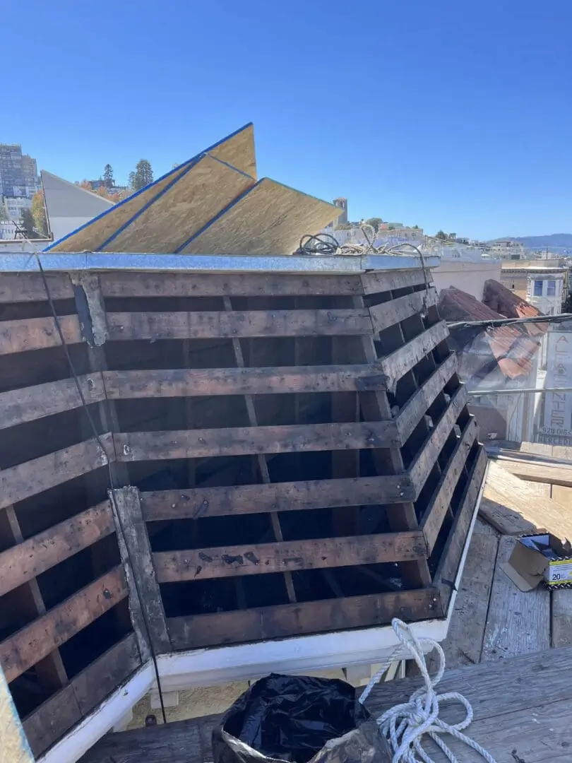 Wooden roof structure under construction, clear sky.